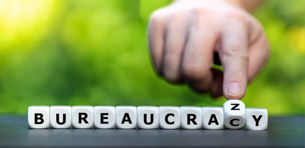 istock Hand turns dice and changes the word bureaucracy to bureaucrazy. Symbol for a complicate bureaucracy. 2081385674