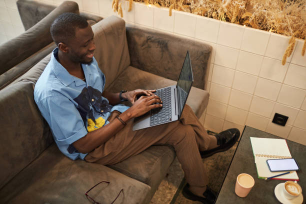 istock Black man using laptop sitting on couch in office and smiling 2081387261