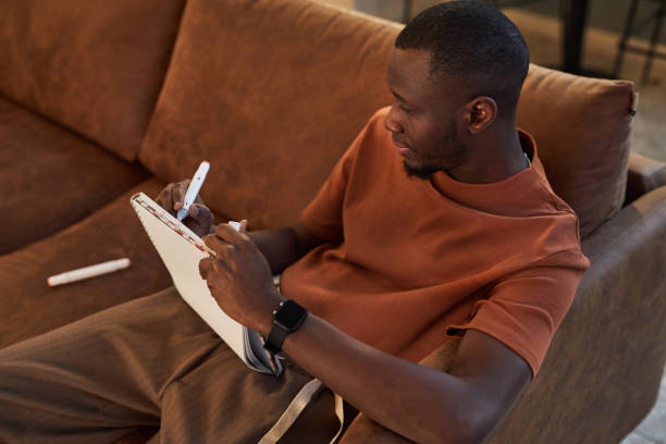 istock Black Man Drawing Sketches Sitting on Comfortable Couch 2081387289