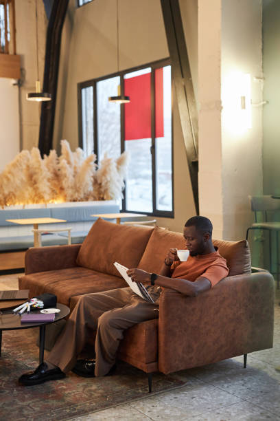 istock Black Man with Cup of Coffee Relaxing on Couch 2081387294
