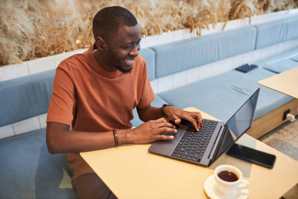 Black Man using Laptop in Coffee Shop and Typing