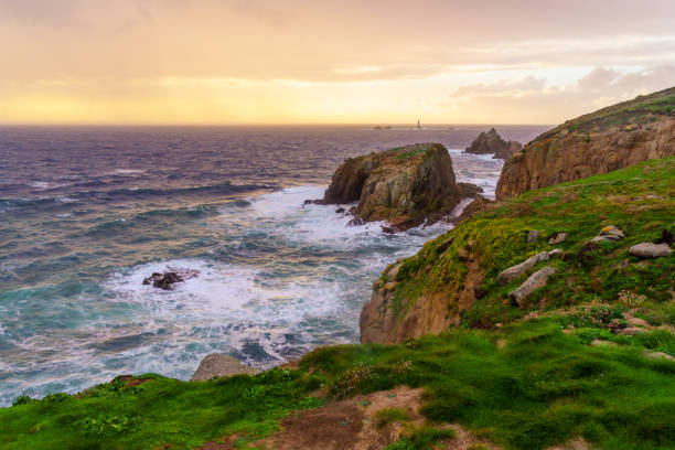 Sunset view of the Lands End coastline landscape, with the Longships Lighthouse, in Cornwall, England, UK