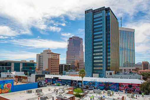 A-mid the skyscrapers, workers painting flat roofs with reflective elastomeric paint to repel the rains and the summer heat of Tucson, Arizona