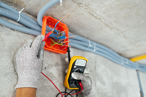 Electrician testing voltage at a construction site during home or apartment renovation, repair or reconstruction