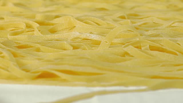handmade Italian egg pasta: old woman cutting fettuccine at home with a cutter