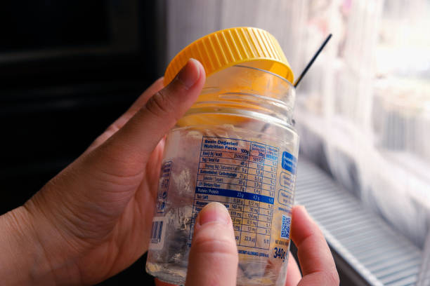 Woman checking label of empty peanut butter jar. Ingredient control, nutritional values, fat, carbohydrate and protein content