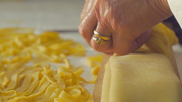 closeup on hands cutting tagliatelle: Fresh handmade Italian pasta