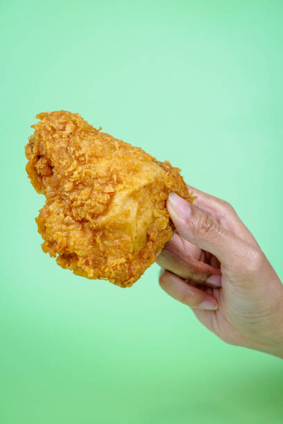 istock Female hand holding fried chicken on green background. 2081457876