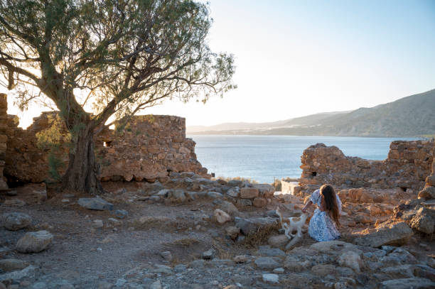 Woman explores ruins above sea at sunset