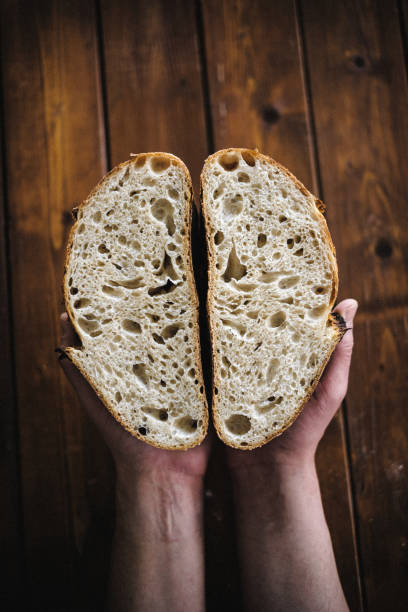 istock Hands holding artisan sourdough bread cut in half 2081470760