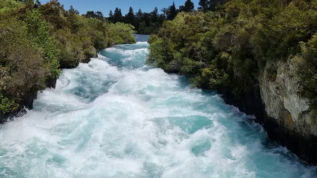 slow motion of the spectacular Huka Falls rapids flowing down the canyon surrounded by native bush in New Zealand