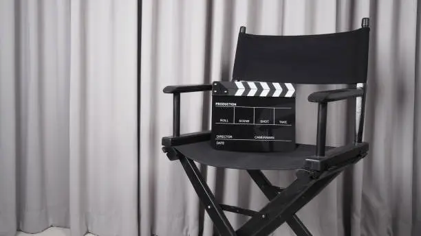 Photo of Clapper board or movie slate with black director chair use in video production , movie, cinema industry.