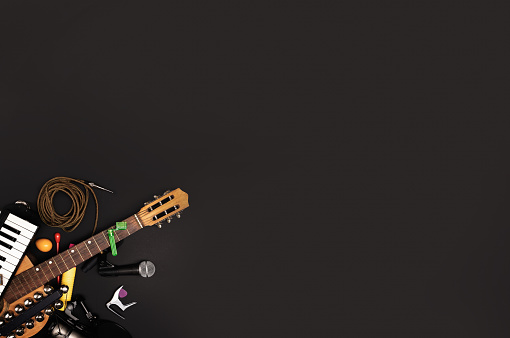 Musician's workspace with various instruments and recording accessories on a dark surface - Creative process and music arrangement concept - flat lay background for banner and ads.