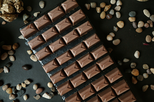 A delicious chocolate bar surrounded by a variety of nuts, offering a delightful combination of textures and flavors.
