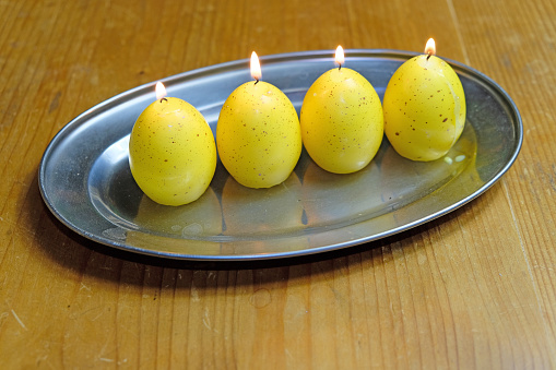 Decoration for Easter, four burning egg-shaped candles on a silver tray