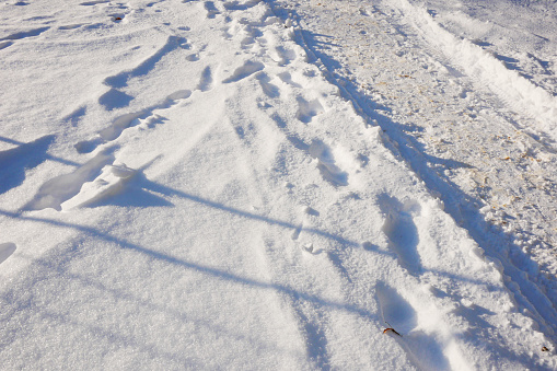 Road and human footprints on the snow surface. Fragment of a village road in the snow.