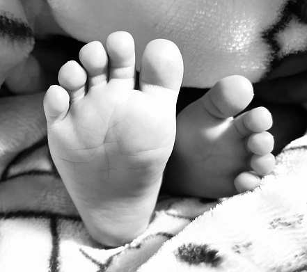 In frame is black and white click of an infant feet