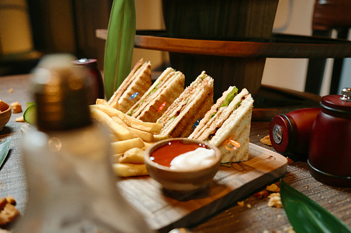 A plate filled with a selection of sandwiches and a side of golden French fries resting on a table.