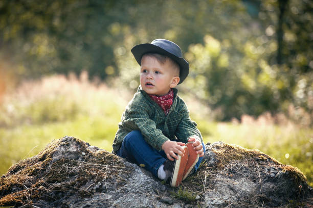 istock Cute Little Happy Boy with Hat Sitting in Summer Forest 2081637988