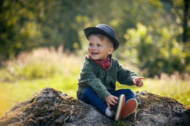 istock Cute Little Happy Boy with Hat Sitting in Summer Forest 2081637994