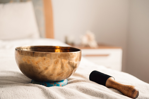 An inviting scene of a Tibetan singing bowl on a bed, ready for a sound healing session with soft morning light