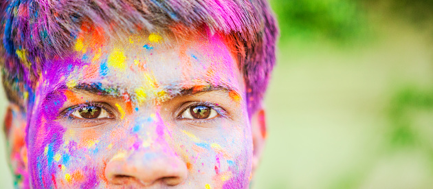 Portrait of a young man covered in colored dye while celebrating the festival of Holi in Jaipur, India.