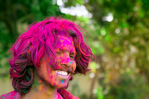 Portrait of a young man covered in colored dye while celebrating the festival of Holi in Jaipur, India.
