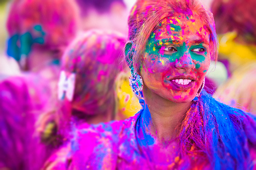 Portrait of a young woman covered in colored dye while celebrating the festival of Holi in Jaipur, India.