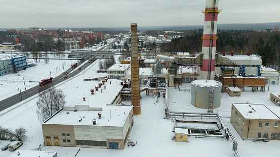 Drone photography of inside of a power plant in a city covered by snow during winter cloudy day