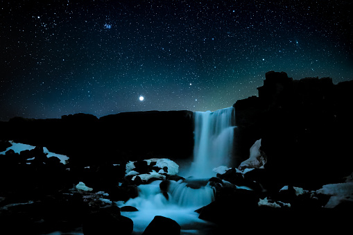 Oxararfoss waterfall at clear sky night with stars and a bit of light from dawn