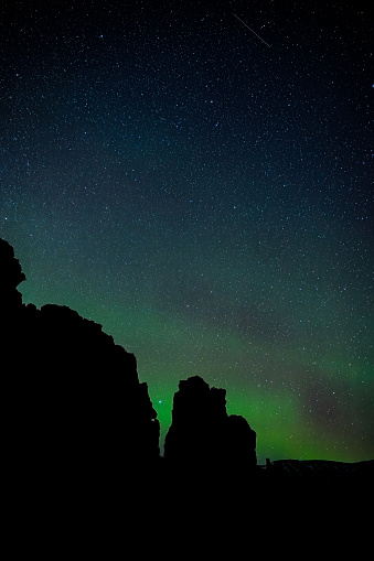 Green aurora with a sky full of stars in the canyon at Thingvellir Natural Park in Iceland