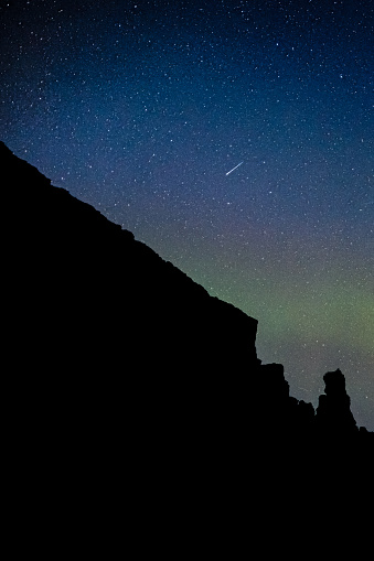 Green aurora with a night sky shooting star in the canyon at Thingvellir Natural Park in Iceland