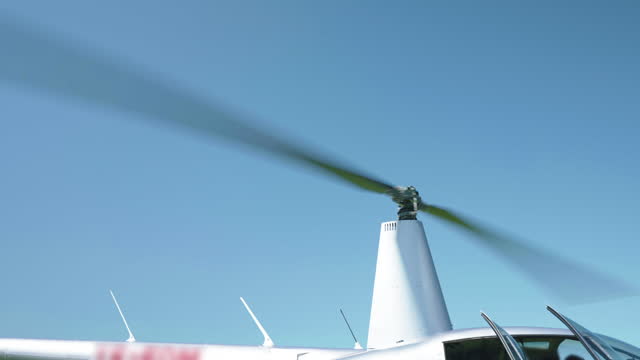 Helicopter rotating blades against blue sky background, powerful engine of aircraft keep moving rotor blades while landing or taking off