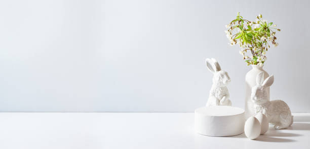 istock Empty round white podium for product presentation. Spring flowers in a vase and easter eggs on a light background 2081693239