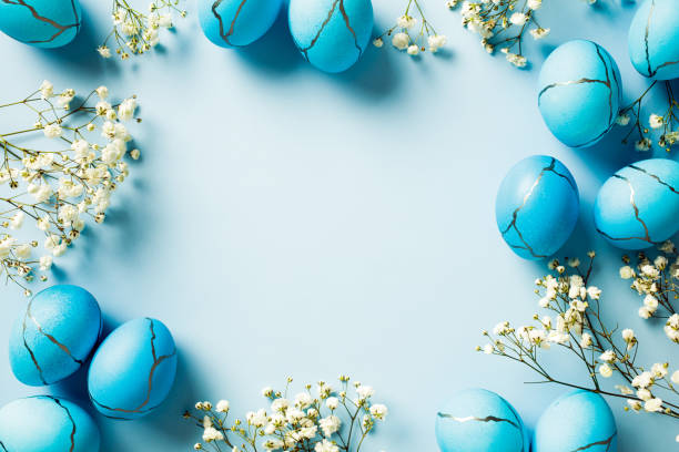 istock Stylish Easter eggs with white minimal flowers on pastel blue background. Flat lay, top view, copy space. 2081704246