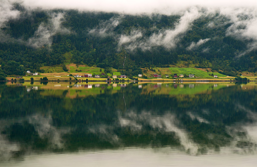 Foggy landscape with mirror reflexion in fjord water