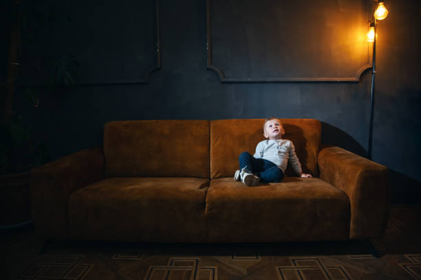 istock Adorable Little Cute Boy on Vintage Sofa in Dark Interior 2081724981