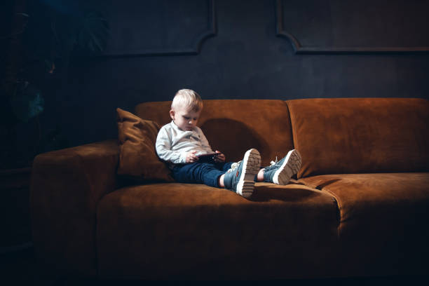 istock Handsome Little Rich Boy with Smartphone Sitting in Dark Interior 2081724990