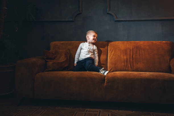 istock Adorable Little Cute Boy on Vintage Sofa in Dark Interior 2081725543