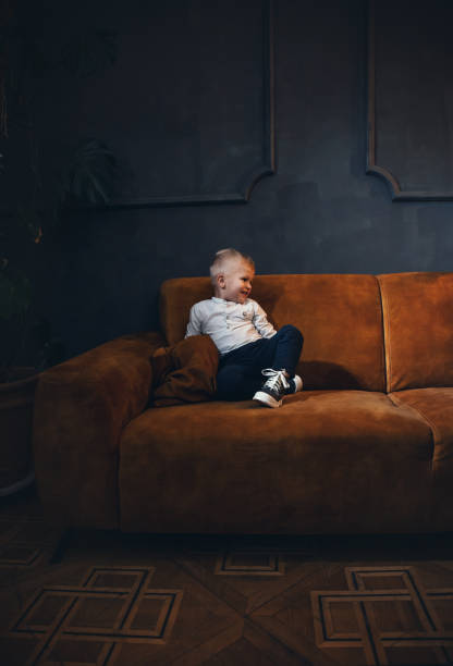 istock Adorable Little Cute Boy on Vintage Sofa in Dark Interior 2081725612
