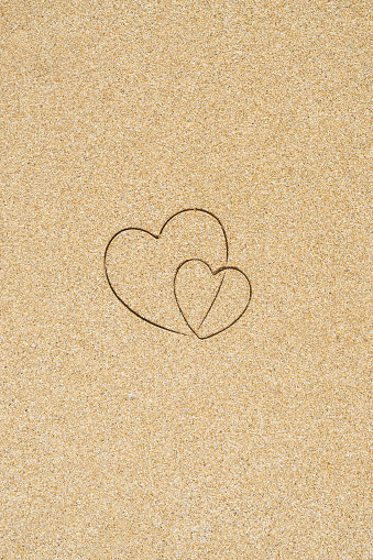 Hand-drawn shape of two heart on sand tropical beach. valentines day. Holiday concept. Creative, background, copy space, travel, summer. Flat lay