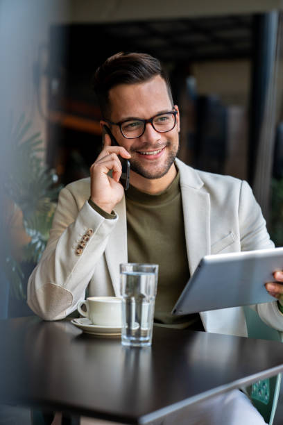 istock Smiling young businessman talking on cellphone and using digital tablet 2081760009
