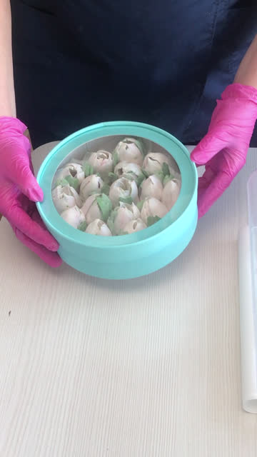 A woman demonstrates a marshmallow in a hat box. Closes the box with a lid. Tulips from marshmallows. Homemade marshmallows. Vertical video.