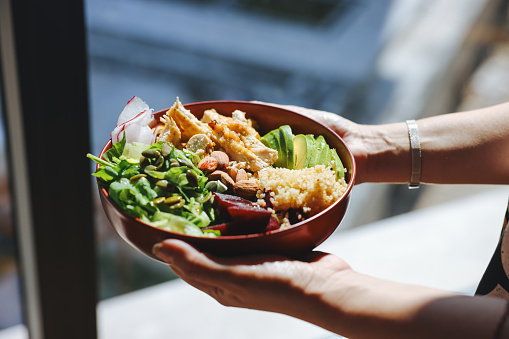 Healthy salad with fresh vegetables.View from above. Closeup image of a woman holding and eating chicken salad