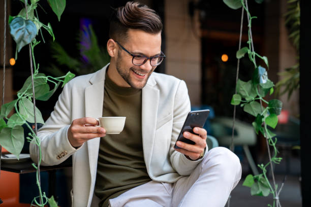 Smiling businessman sending a text message to his business clients