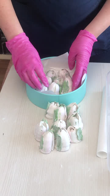 A woman folds a marshmallow in a hat box. Tulips from marshmallows. Homemade marshmallows. The box is turquoise in color. Vertical video.