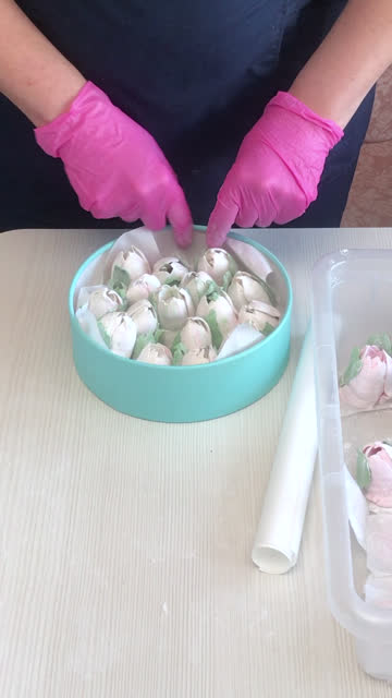A woman folds a marshmallow in a hat box. Tulips from marshmallows. Homemade marshmallows. The box is turquoise in color. Vertical video