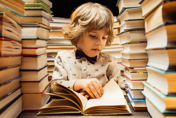 istock Handsome little child flips through the book pages in library. Elementary school boy enjoying reading in bookshop or bookstore 2081802140