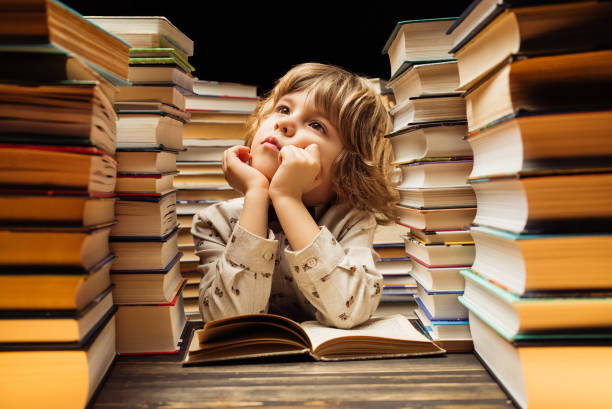 istock Dreamy little boy sitting at classroom or library desk. Smart child smiling, thinking about study or maybe school holidays, end of lesson 2081802148