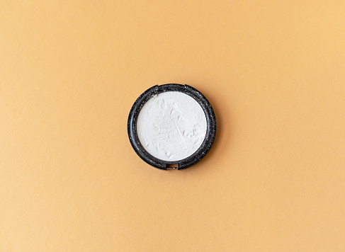 rice white powder in a round box, peach fuzz color background